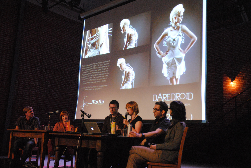 Panel of designers on stage at IndieCade 2011 in front of a screen showing the DareDroid project
